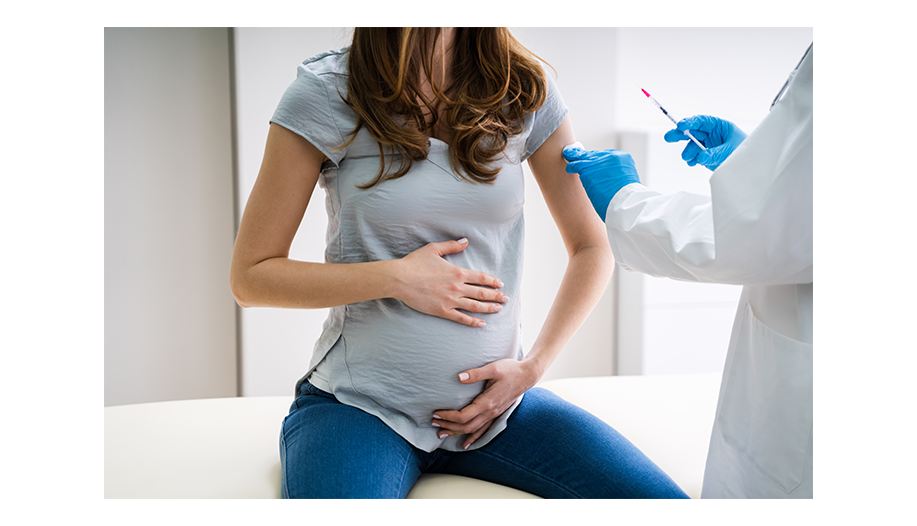 Schwangere Frau sitzt beim Arzt und wird geimpft