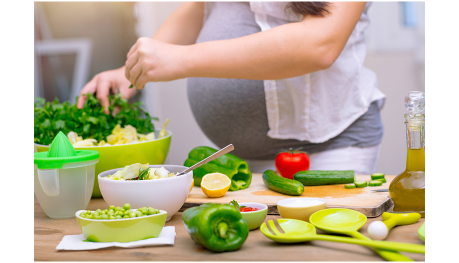Schwangere Frau bereitet einen grÃ¼nen Salat zu